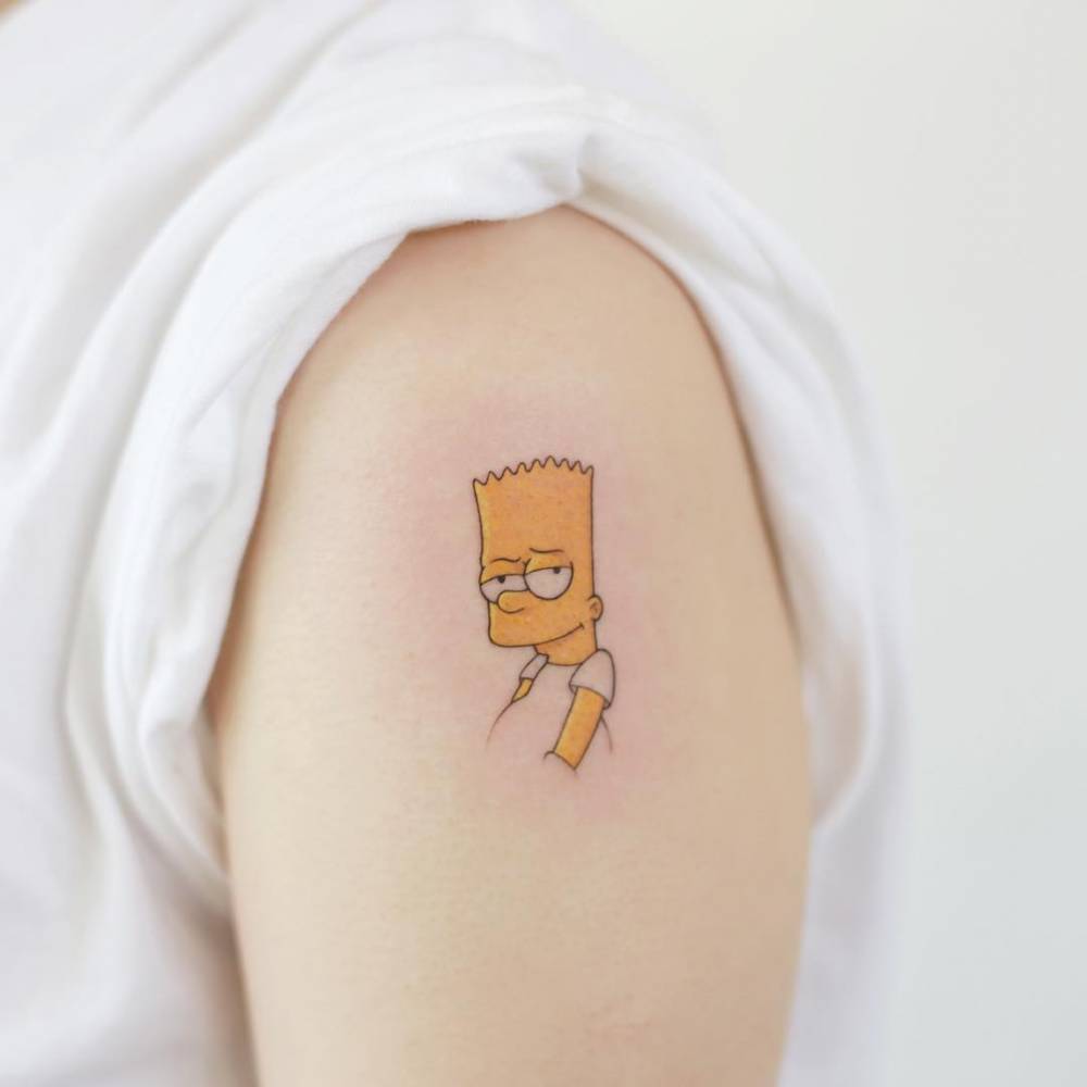 Um tatuagem de personagem de desenho animado no bra&ccedil;o de uma pessoa com camiseta branca.