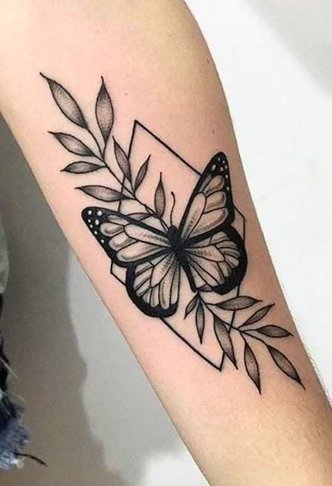Tatuagem de borboleta com folhas e formas geom&eacute;tricas no bra&ccedil;o de uma pessoa.