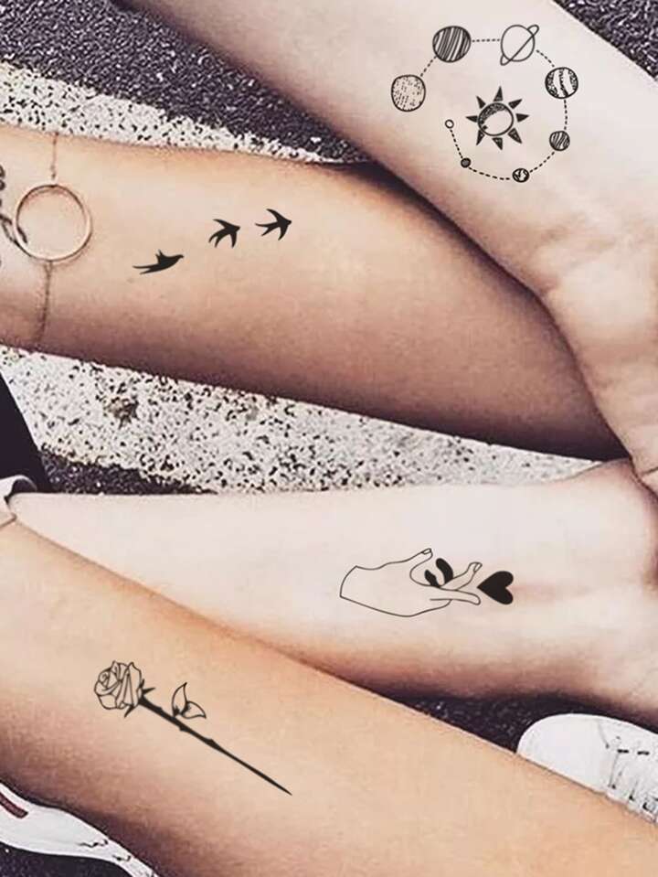 Tr&ecirc;s antebra&ccedil;os com tatuagens de planetas, p&aacute;ssaros, uma m&atilde;o segurando cora&ccedil;&otilde;es e uma rosa.