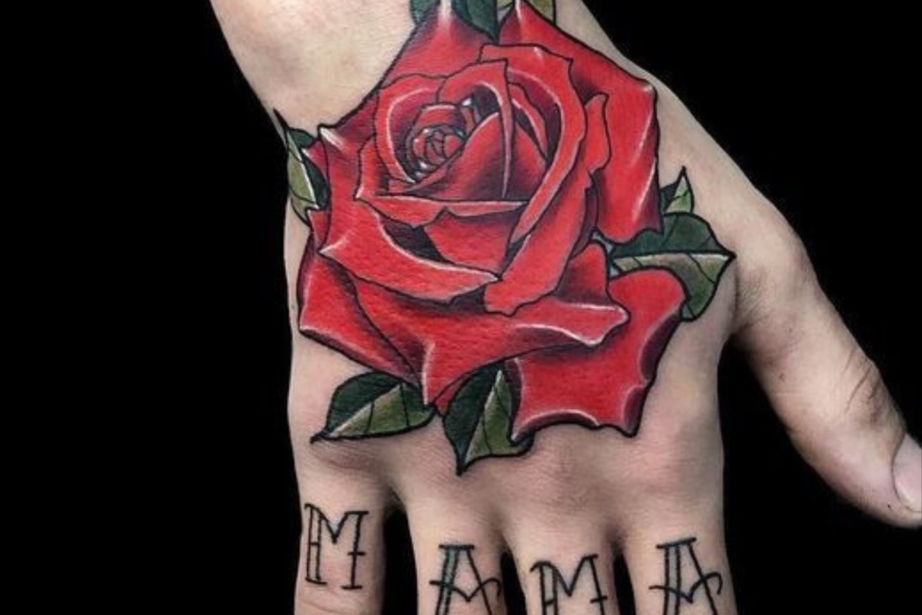 tatuagem-rosa-na-mao-2-1024x683-1 Uma mão com uma tatuagem de rosa vermelha e a palavra "MAMA" escrita nos dedos.