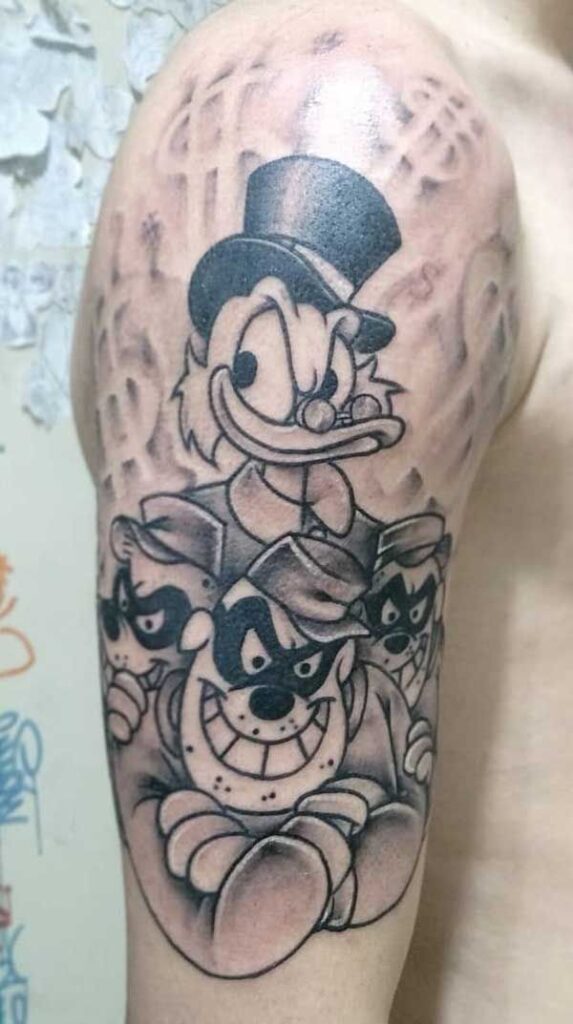 Tatuagem no bra&ccedil;o com personagens animados sorridentes, um com cartola e outros com m&aacute;scaras, em fundo de cifr&otilde;es.