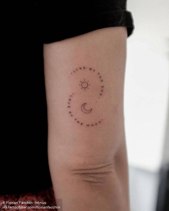 Bra&ccedil;o com tatuagem de sol e lua, cercada por frase em ingl&ecirc;s, em pele clara.