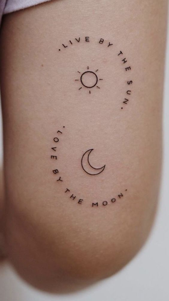 Uma tatuagem com s&iacute;mbolos do sol e da lua, acompanhados por frases em ingl&ecirc;s, est&aacute; vis&iacute;vel na pele.