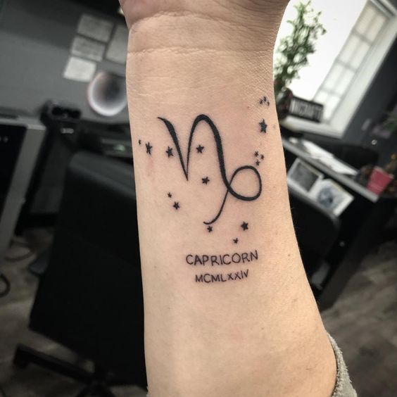 Uma tatuagem no pulso com o símbolo de Capricórnio, estrelas e números romanos.