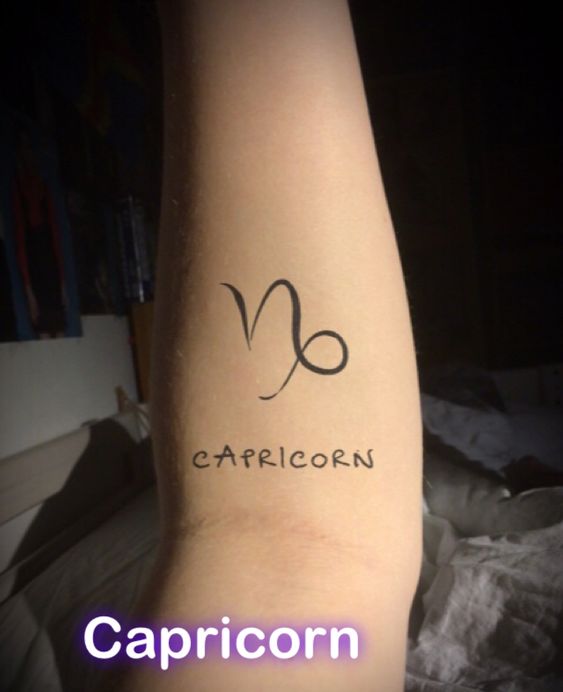 Braço com tatuagem do símbolo e nome do signo de Capricórnio.