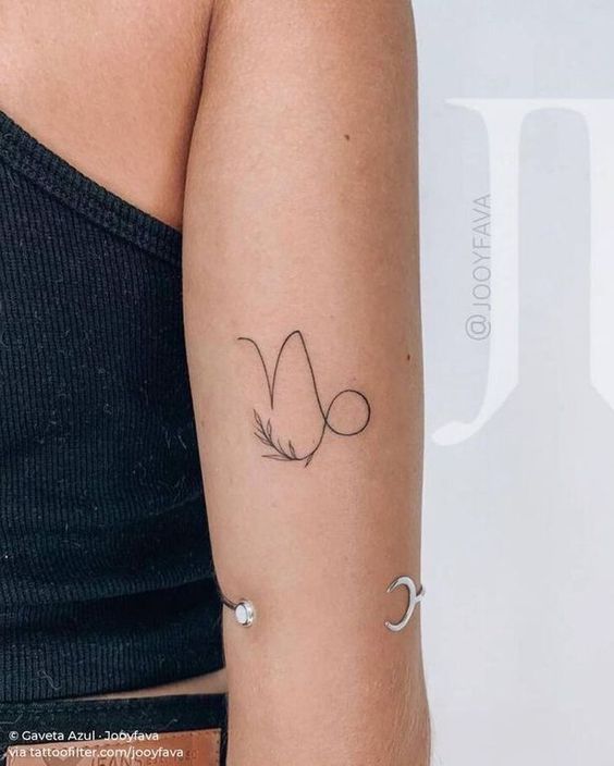 Pessoa com tatuagem minimalista de símbolo astrológico no braço, usando uma blusa sem mangas.