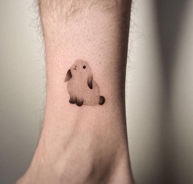 Tatuagem de coelho em estilo minimalista no tornozelo de uma pessoa.