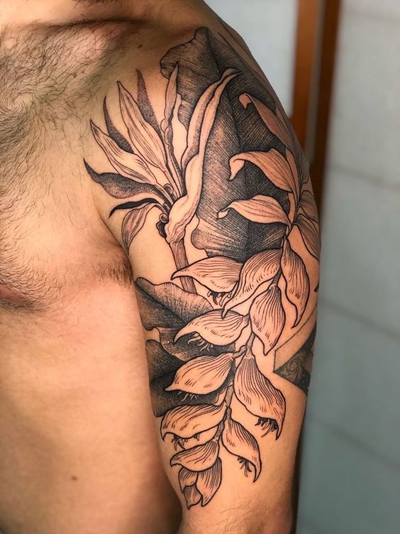 Tatuagem de folhas e flores no ombro de uma pessoa, com detalhes em preto e sombreado.