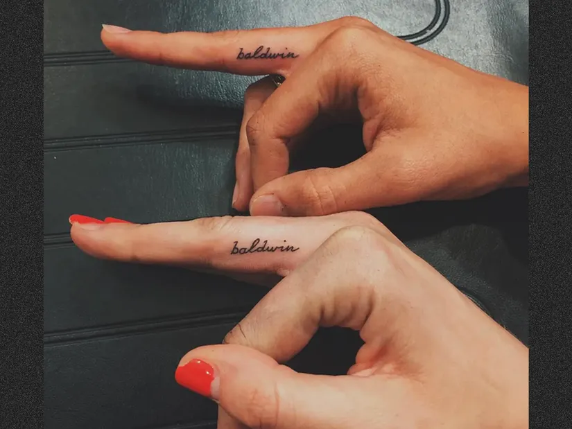 Dois dedos com tatuagens id&ecirc;nticas com a palavra "baldwin" em letra cursiva.