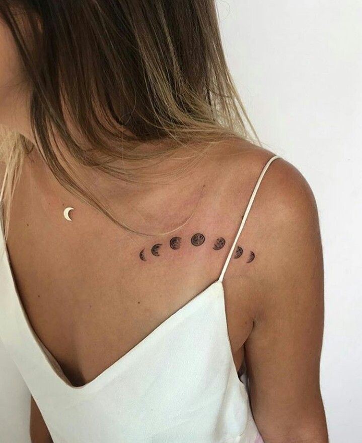 Pessoa com vestido branco, exibe tatuagem das fases da lua no ombro e colar com pingente de lua.