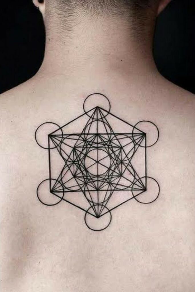 tataugem-de-cubo-683x1024-1 Tatuagem geométrica com linhas e círculos entrelaçados na parte superior das costas de uma pessoa.