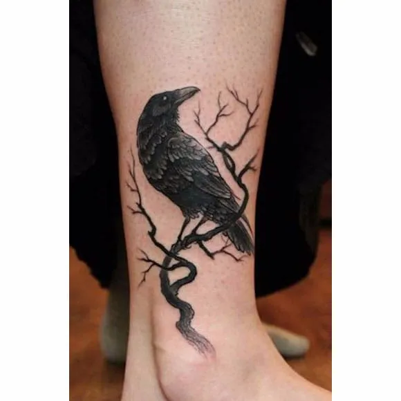 significado-tatuagem-de-corvo-2 Tatuagem de corvo preto pousado em galho seco na perna de uma pessoa.