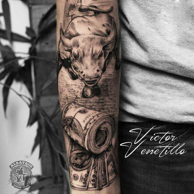 Um bra&ccedil;o tatuado com a imagem de um touro e notas de dinheiro enroladas.