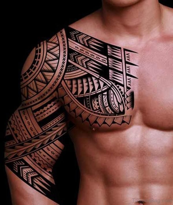 tatuagem-maori-masculina-nos-ombros-peitoral-braco Homem sem camisa com tatuagem tribal detalhada cobrindo ombro e peito, exibindo padrões geométricos.