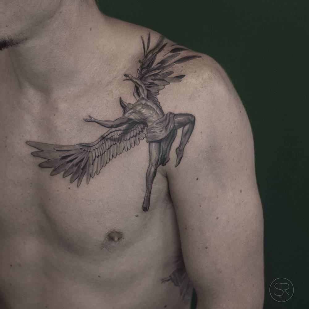 Homem com tatuagem de anjo alado no ombro e peito, em fundo verde escuro.