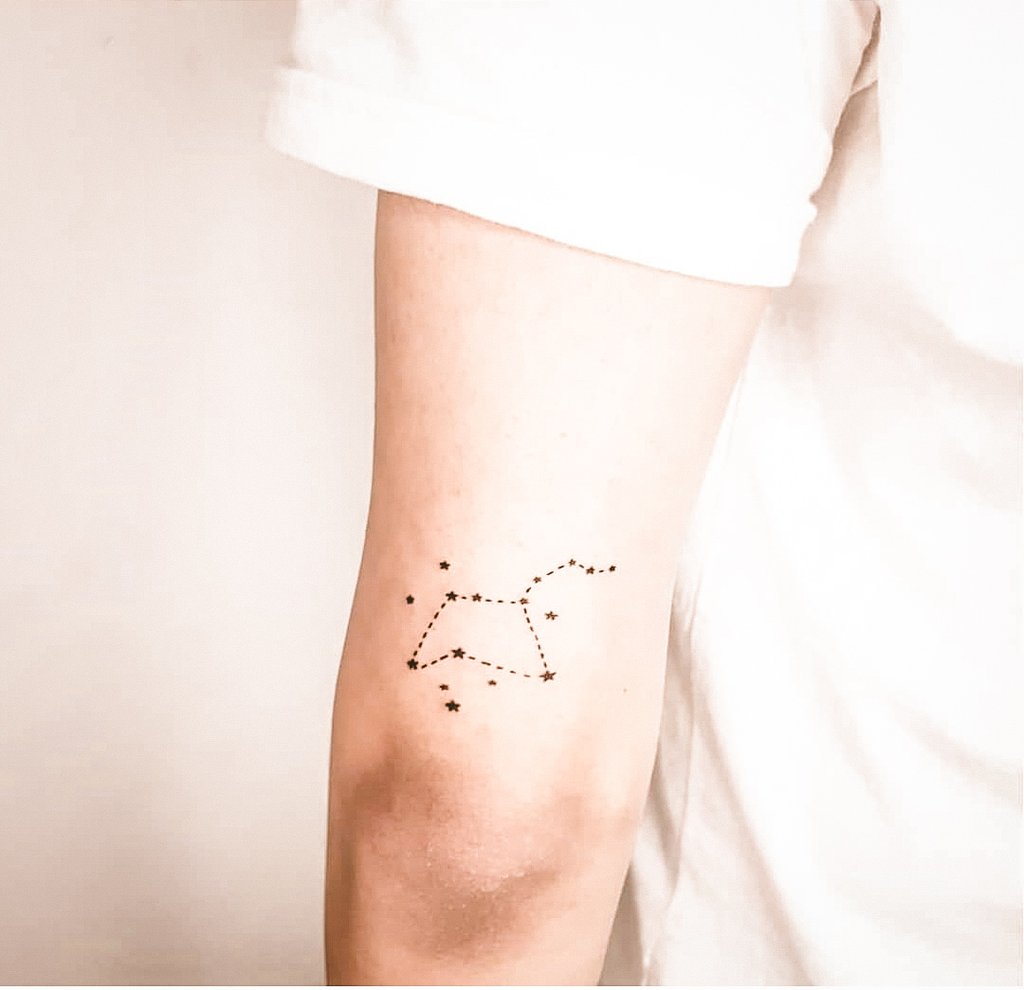 w1024-66 Braço com tatuagem de constelação em linha pontilhada, em fundo claro.