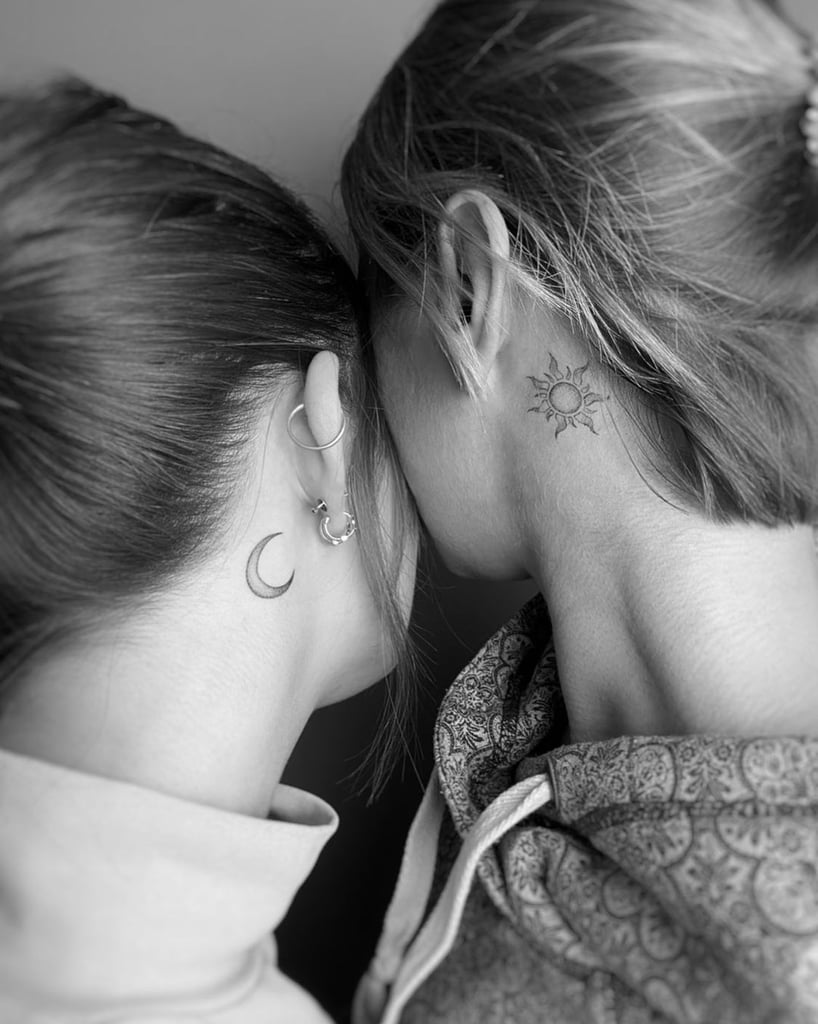 Detalhe de tatuagens combinando de lua e sol na nuca de duas pessoas abraçadas.