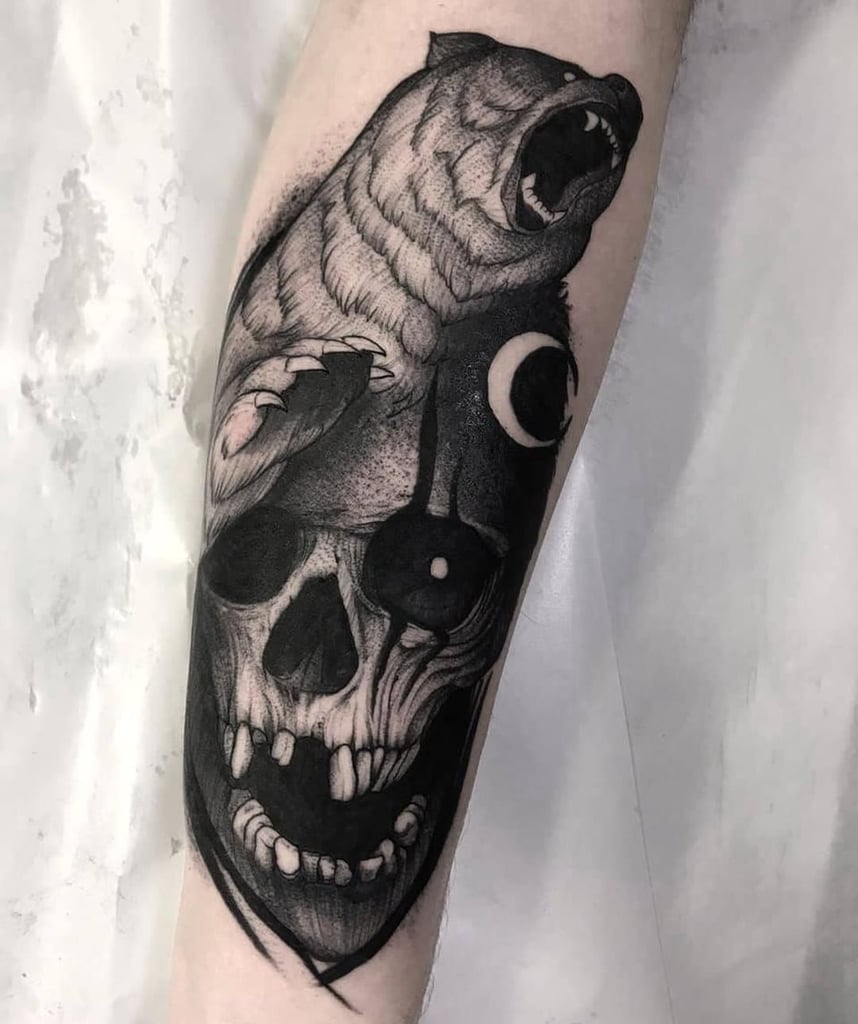 w858-2 Uma tatuagem em um braço com um urso rugindo sobre um crânio.