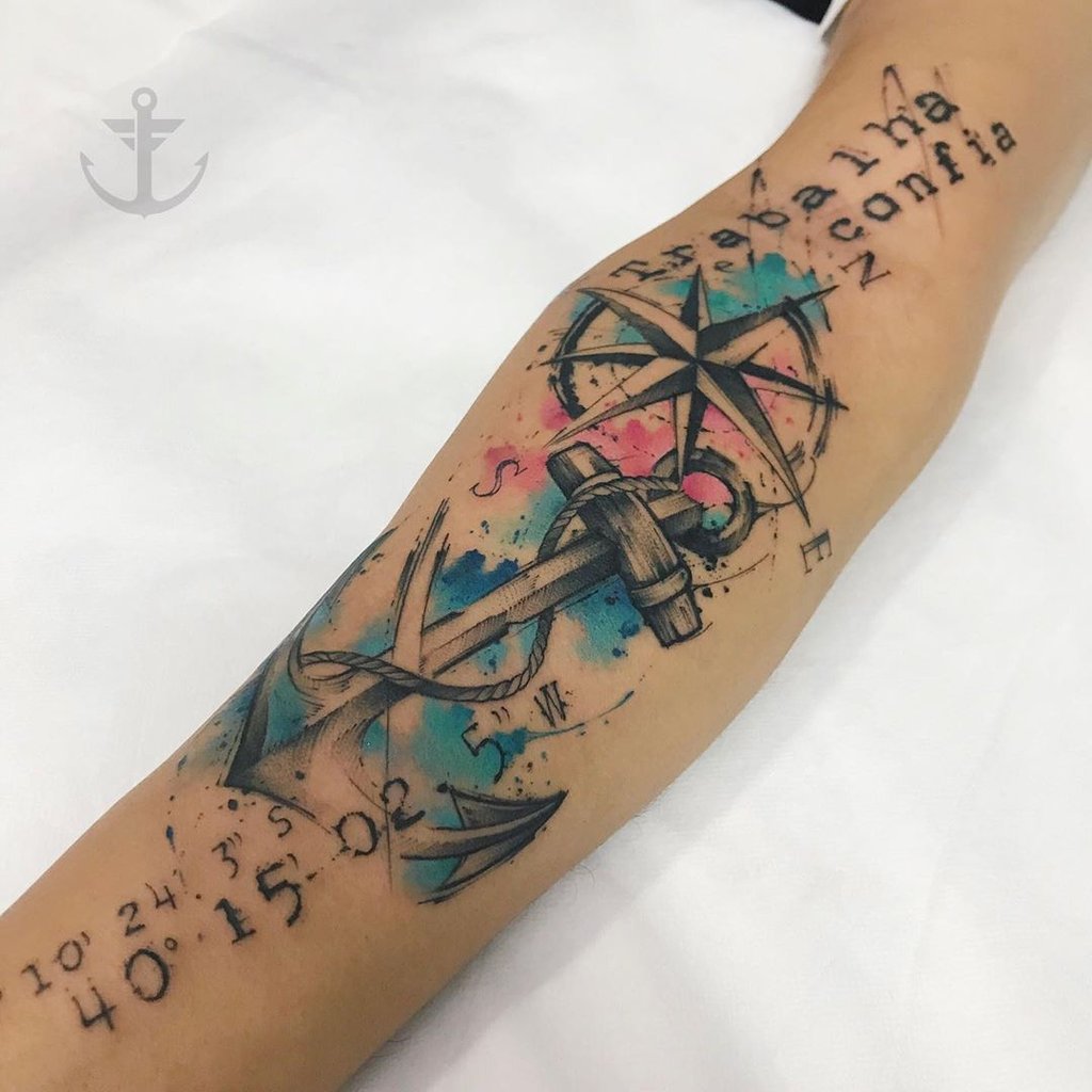 w1024-258-5 Braço com tatuagem colorida de âncora, rosa dos ventos, coordenadas e texto "Trabalha e confia".