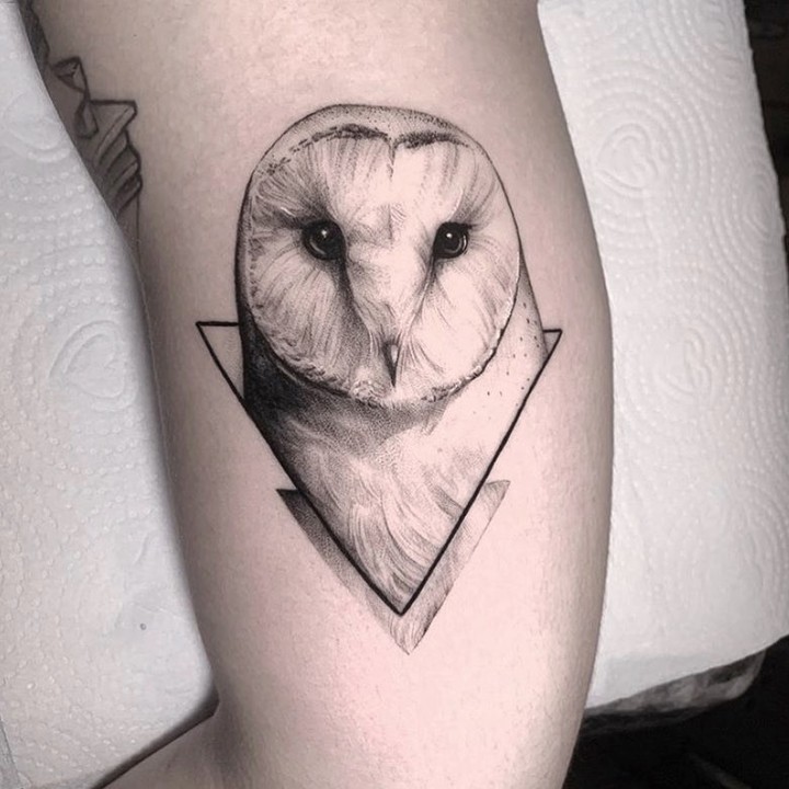 w9999-100 Tatuagem de coruja em estilo geométrico, com detalhes sombreados, no braço de uma pessoa.
