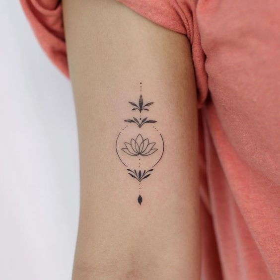 Tatuagem delicada de flor de lótus no braço, design minimalista em preto e branco.