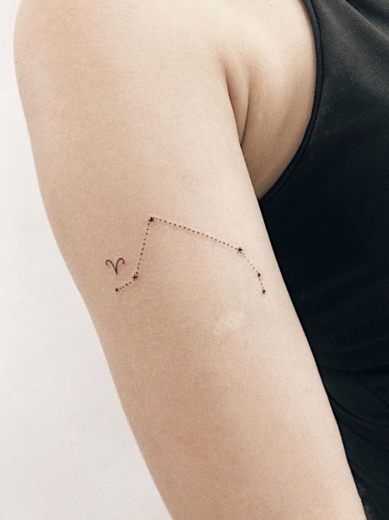 Tatuagem discreta de constelação de Áries no braço. Arte minimalista em pele clara com estrelas e linha pontilhada.