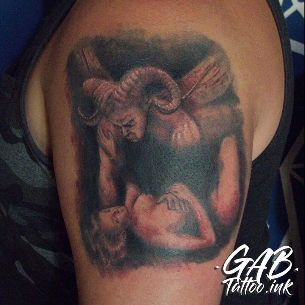 Tatuagem de demônio com chifres segurando uma mulher no braço, arte detalhada no ombro.