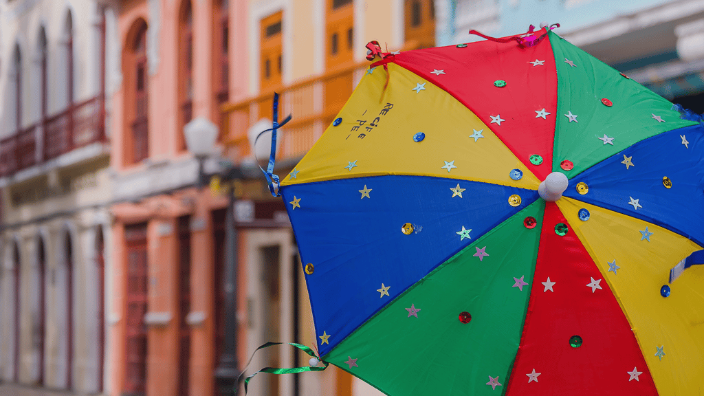 Guarda-chuva colorido decorado com estrelas em frente a prédios históricos em Olinda, Pernambuco.