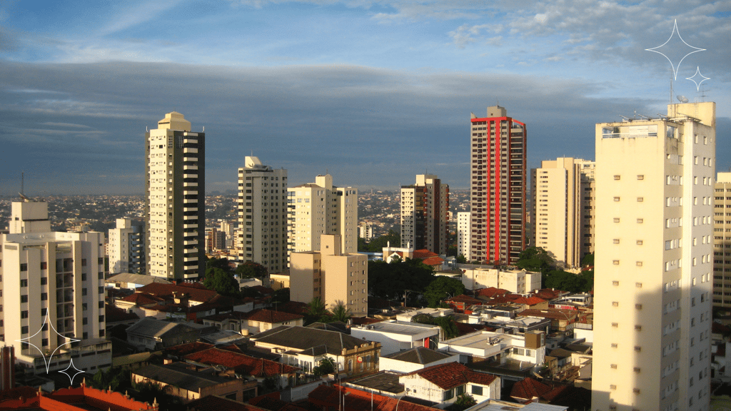 Vista panorâmica de arranha-céus urbanos ao entardecer, céu azul e nuvens ao fundo.