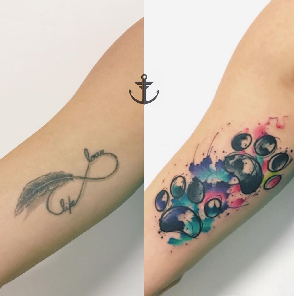Tatuagens de braço: uma com símbolo de infinito, pena e palavras; outra com pegada colorida estilo aquarela.