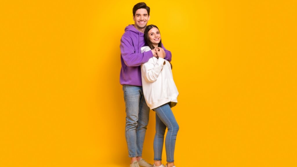 casal abraçado de lado em fundo amarelo