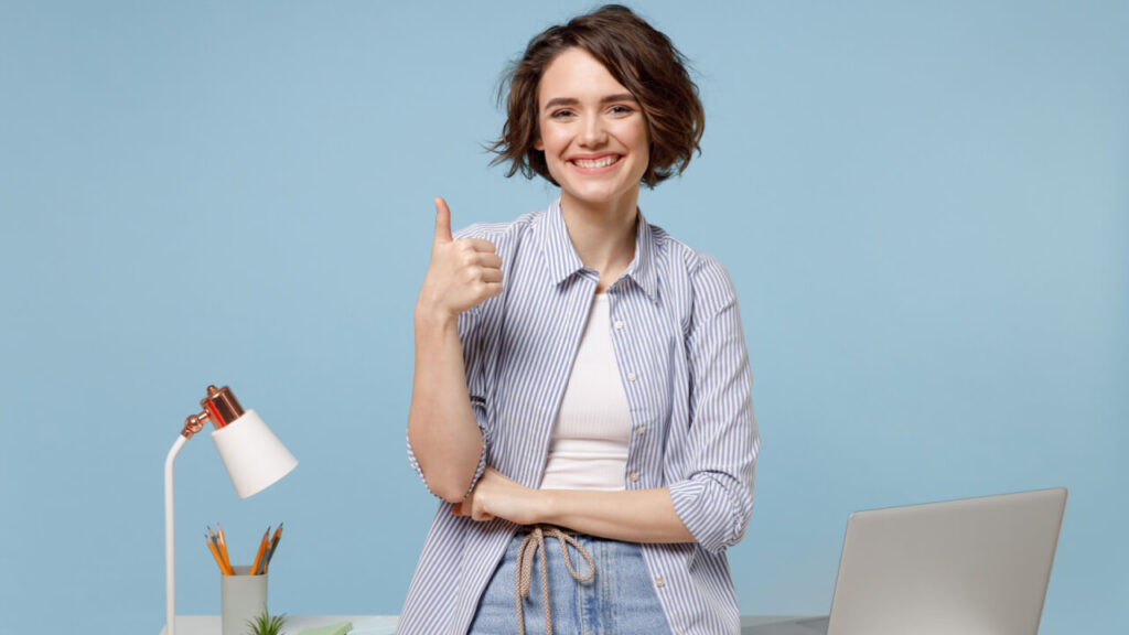 mulher ao centro fazendo um sinal de positivo com a mão em fundo azul