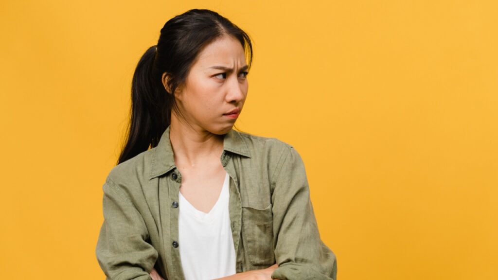 mulher com expressão facial de desconfiada em fundo amarelo