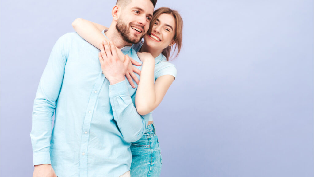 Mulher sorridente e seu namorado. Família feliz e alegre perto da parede roxa no estúdio.
