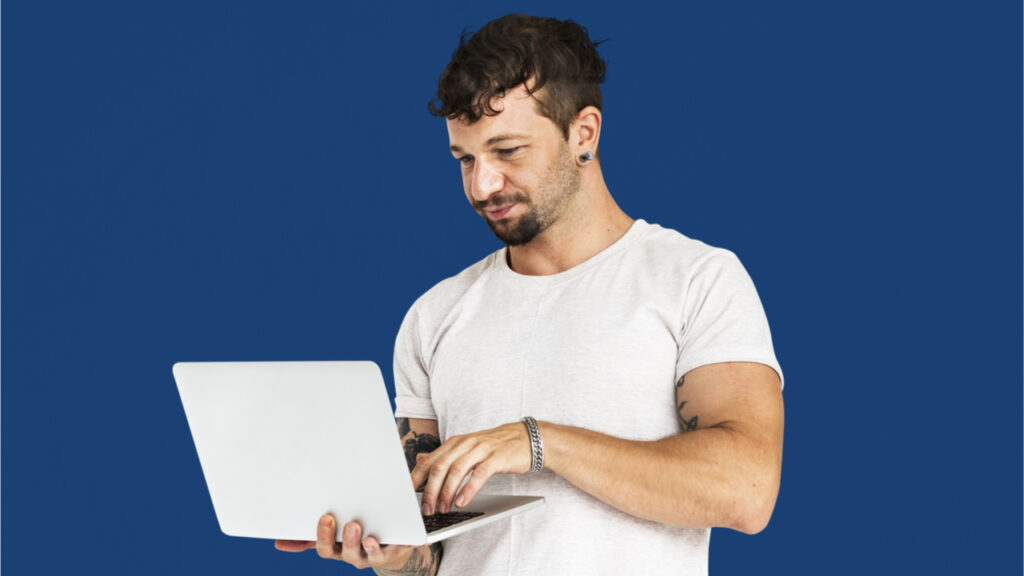 Homem adulto em retrato de estúdio usando dispositivo portátil.