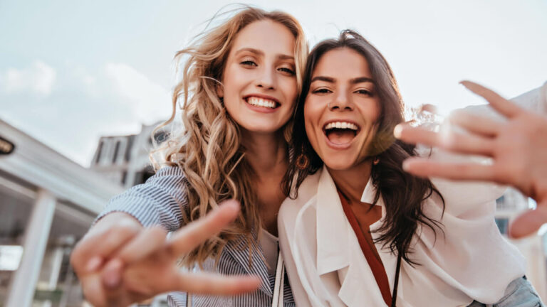 dupla de amigas felizes tirando foto a céu aberto