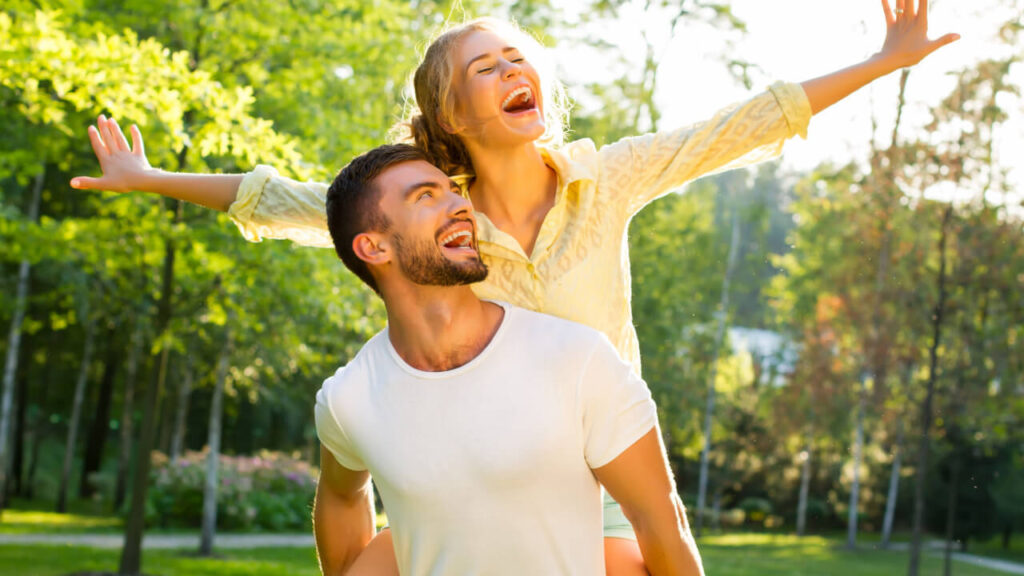casal feliz e sorridente em um parque florestado