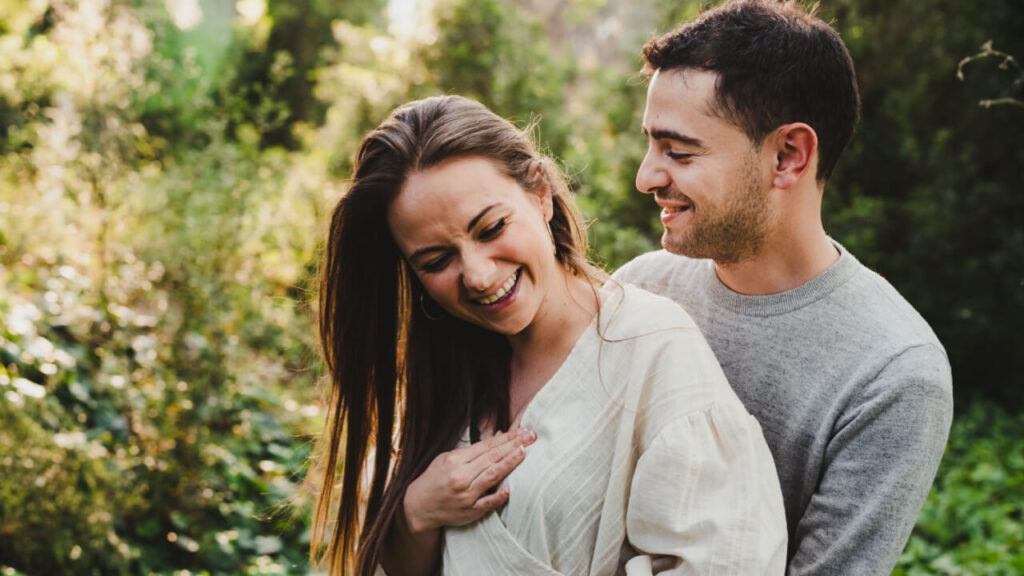 casal heterossexual dando risada em um campo aberto