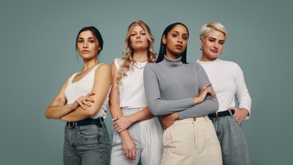 Grupo de mulheres juntas em um estúdio. Quatro mulheres olhando para a câmera em pé contra um fundo de estúdio.