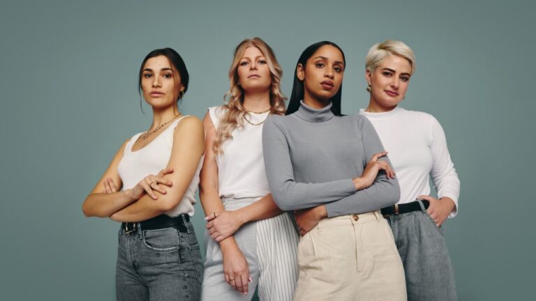 Grupo de mulheres juntas em um estúdio. Quatro mulheres olhando para a câmera em pé contra um fundo de estúdio.