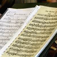 simbolos-nacionais-brasileiros-5_xl Partituras musicais abertas sobre uma superfície, exibindo notas e símbolos musicais detalhados.