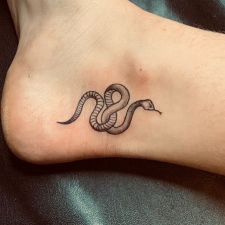 18 uma tatuagem pequena de cobra no pé, próximo ao tornozelo