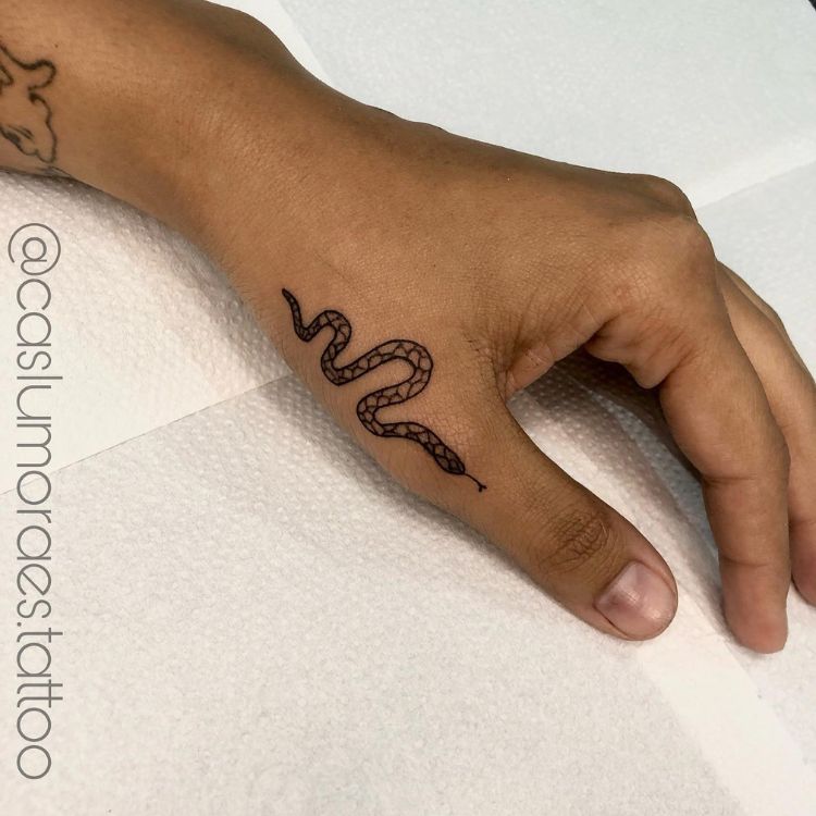 23 Uma mão com uma tatuagem de cobra próxima ao polegar
