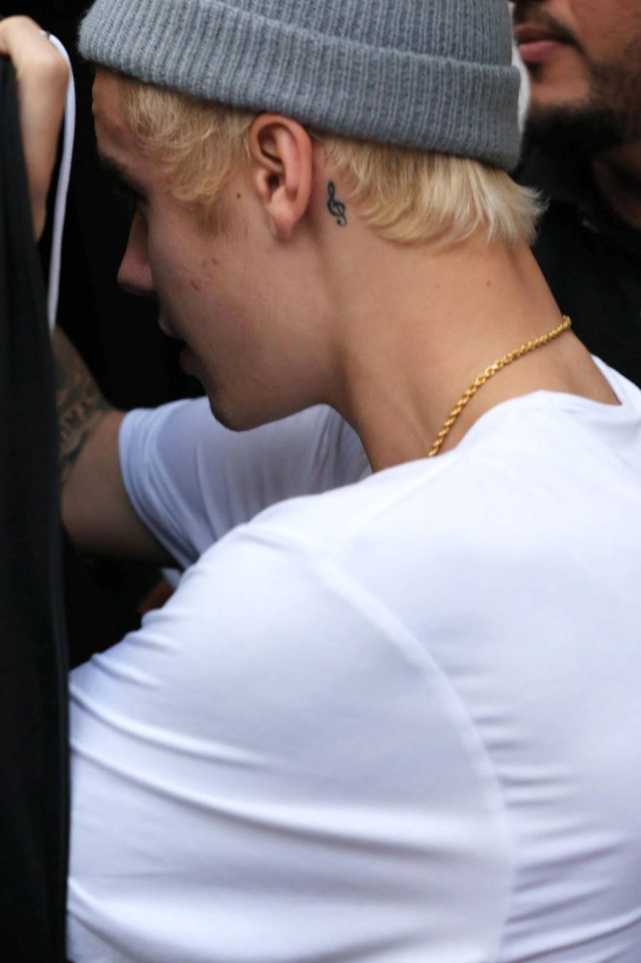 Foto de Justin Bieber de costas mostrando sua tatuagem de clave de sol atrás da orelha