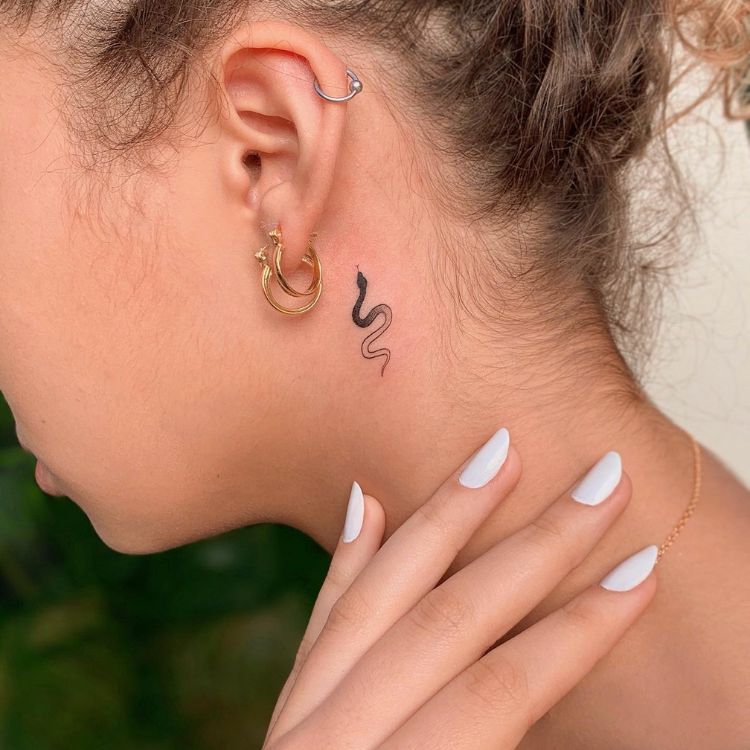 28 Uma mulher loira de perfil, mostrando uma tatuagem de cobra atrás da orelha