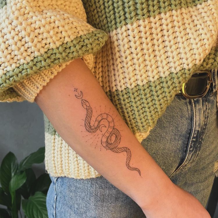 3-4 um braço feminino com uma tatuagem de cobra com duas meia luas