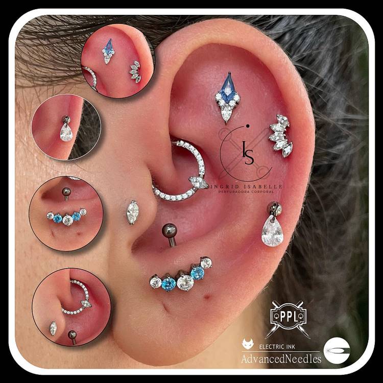 Orelha com piercing no tragus, daith, anti tragus, scapha e hélix, com as joias prateadas com detalhes em azul.