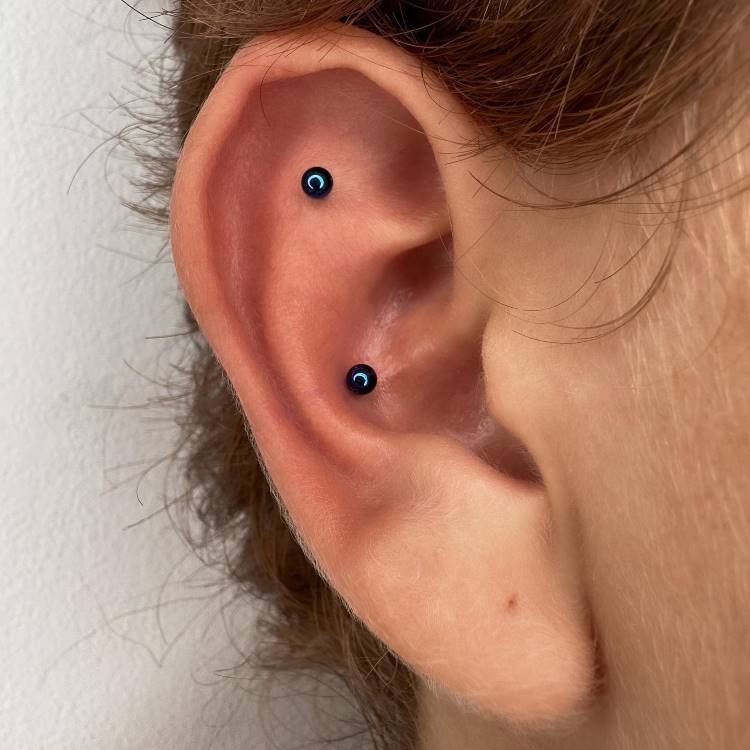 Orelha com piercing em azul na scapha e no conch.