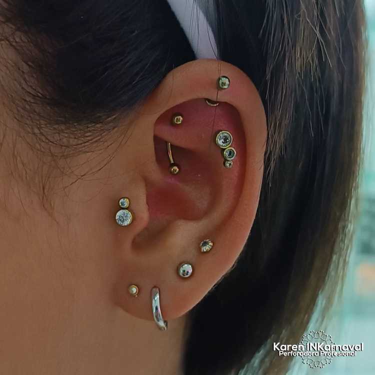 Orelha com piercing duplo no tragus, ponto no flat, triplo na scapha e 4 lóbulo, sendo três bolinhas e uma argola
