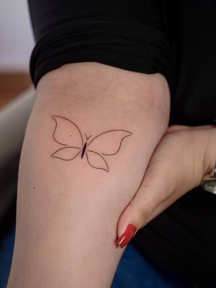 minimalista-braco-borboleta Tatuagem minimalista de borboleta com traços finos em parte interior do antebraço de uma mulher e pele clara.